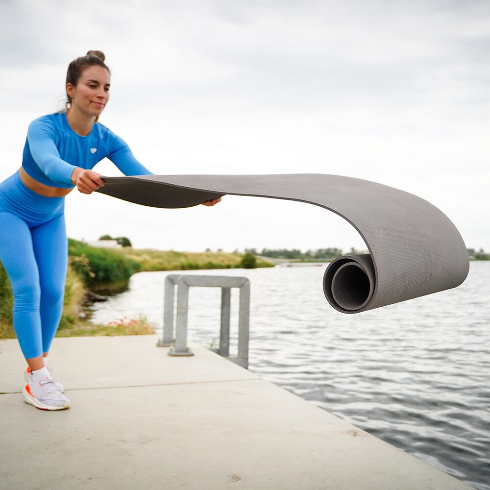 Woman unrolling Tiger Tail grey Yoga Mat