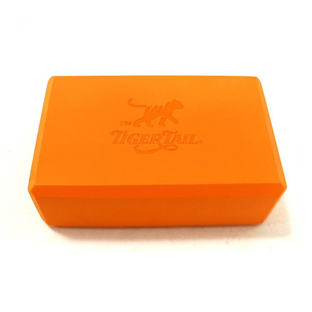 Tiger Tail signature orange yoga block made of supportive, durable foam for stretching and stability.