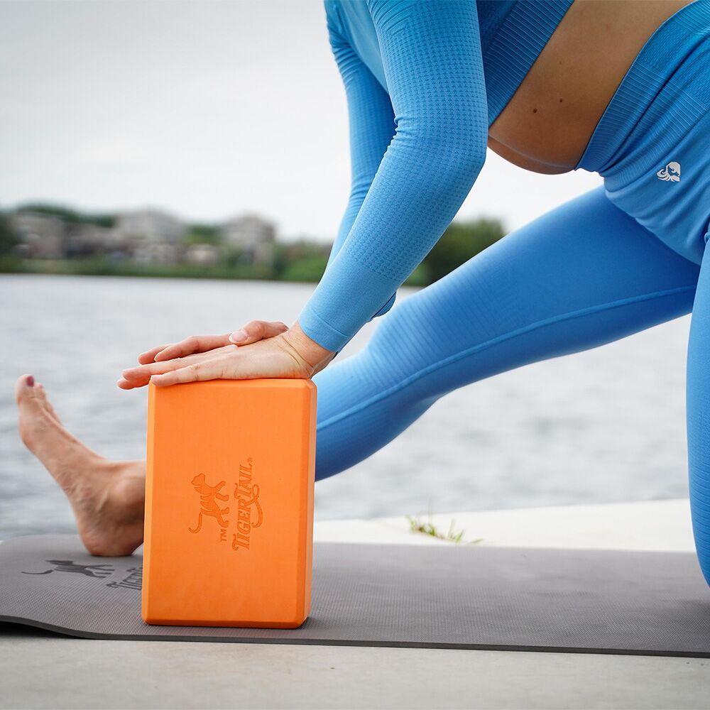 Tiger Tail signature orange yoga block made of supportive, durable foam for stretching and stability.