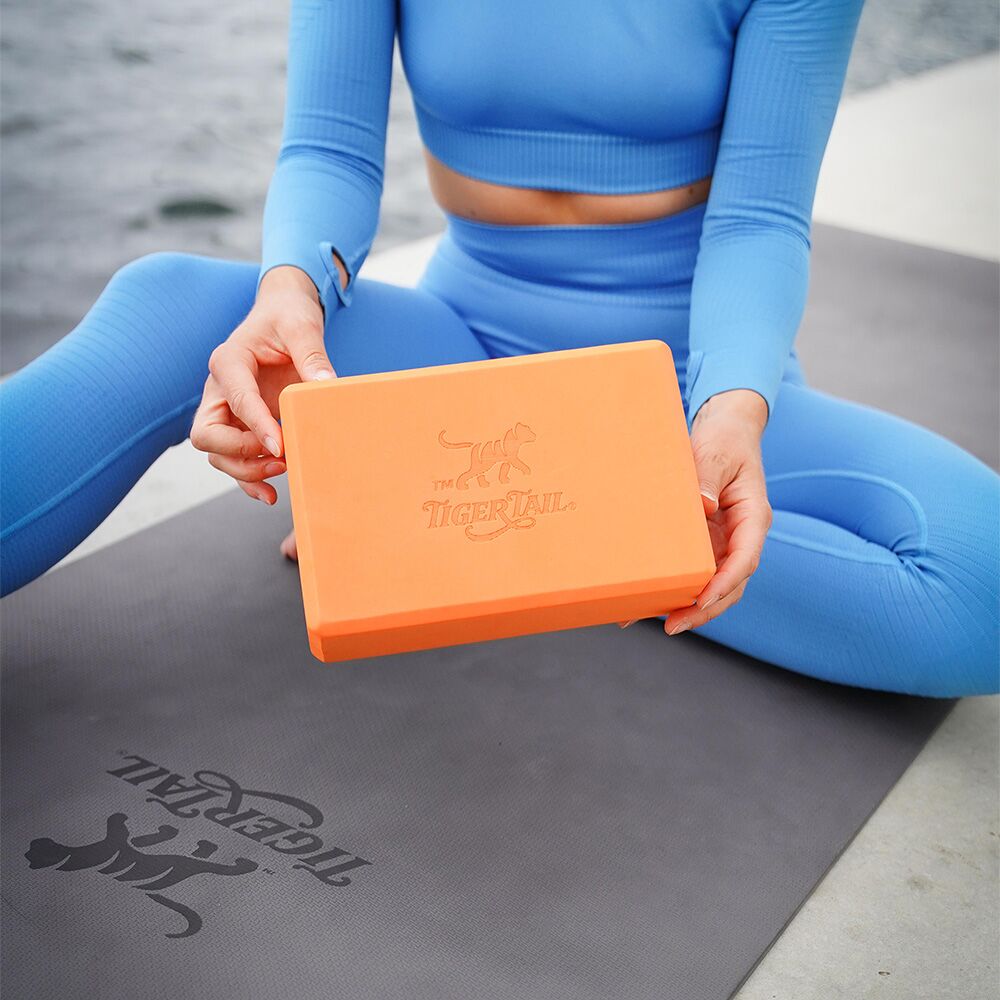 Tiger Tail signature orange yoga block made of supportive, durable foam for stretching and stability.